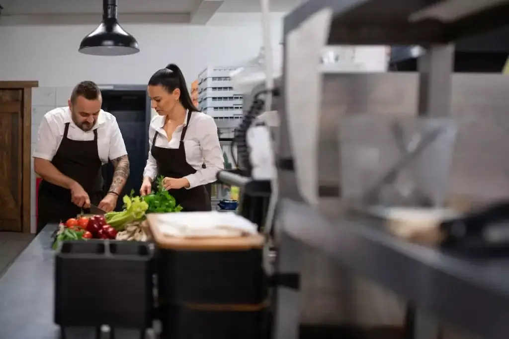 Chefs preparing vegetables in a professional kitchen.