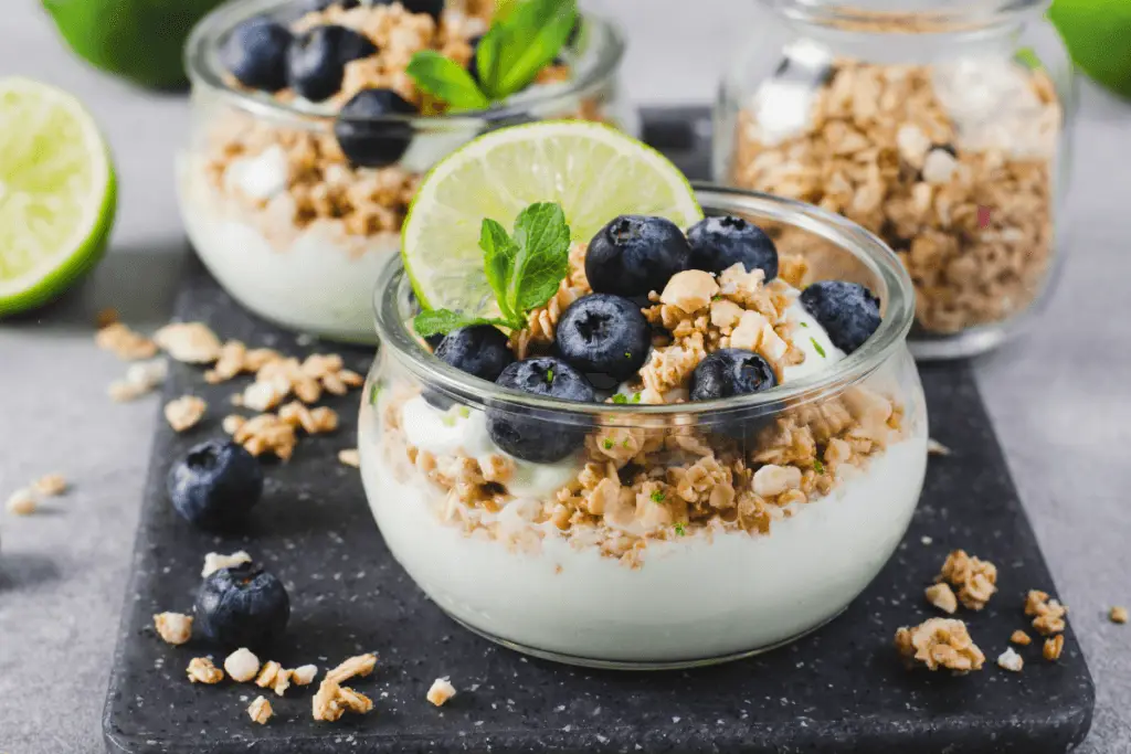 Yogurt with granola, blueberries, lime slice.